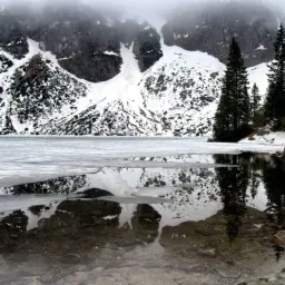 Lodowy Morskie Oko z odbiciem gór i śladem po lawinie.
